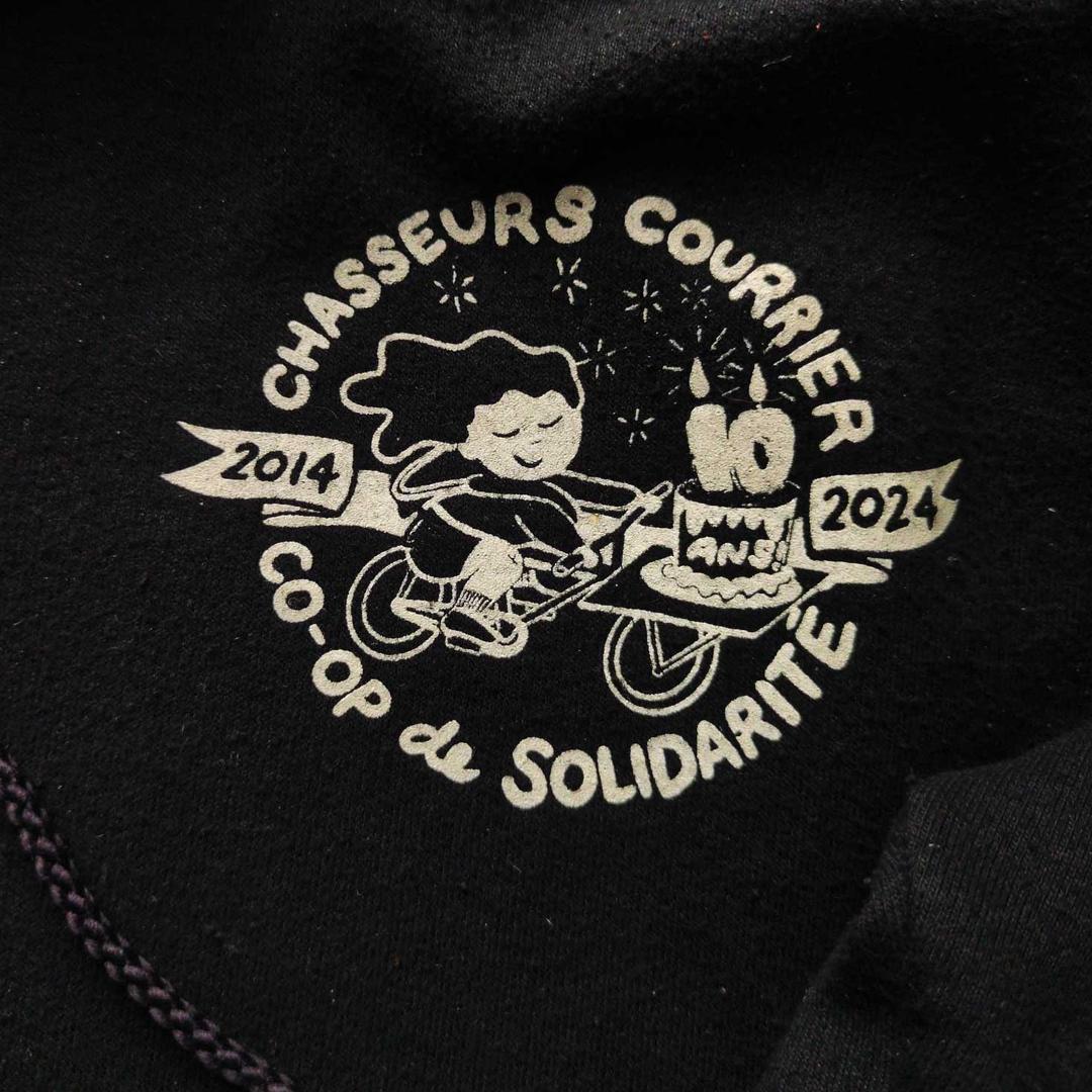 girl rides a cargo bike with a cake that says 10 ans! encicling text reads chasseurs courrier coop de solidarité, 2014-2024